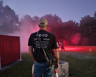 firefighter standing with his back to the camera, wearing a hero shirt